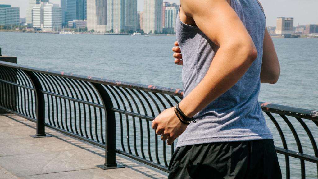 мужчина бежит по набережной с фитнес-браслетом на руке